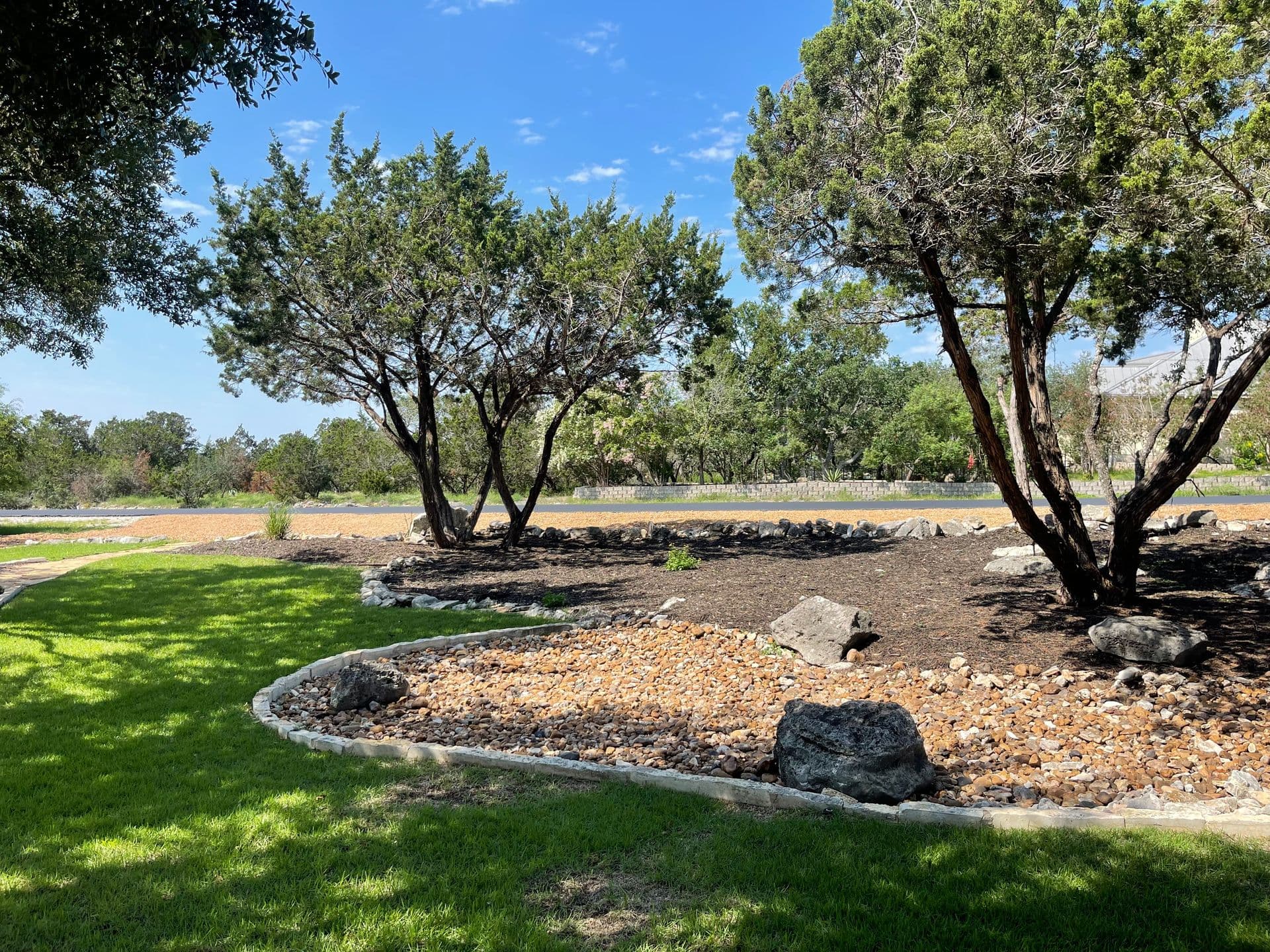 Professional landscaping by Canopy Land Solutions — rock beds, mulch, fresh sod, and mature trees in San Antonio