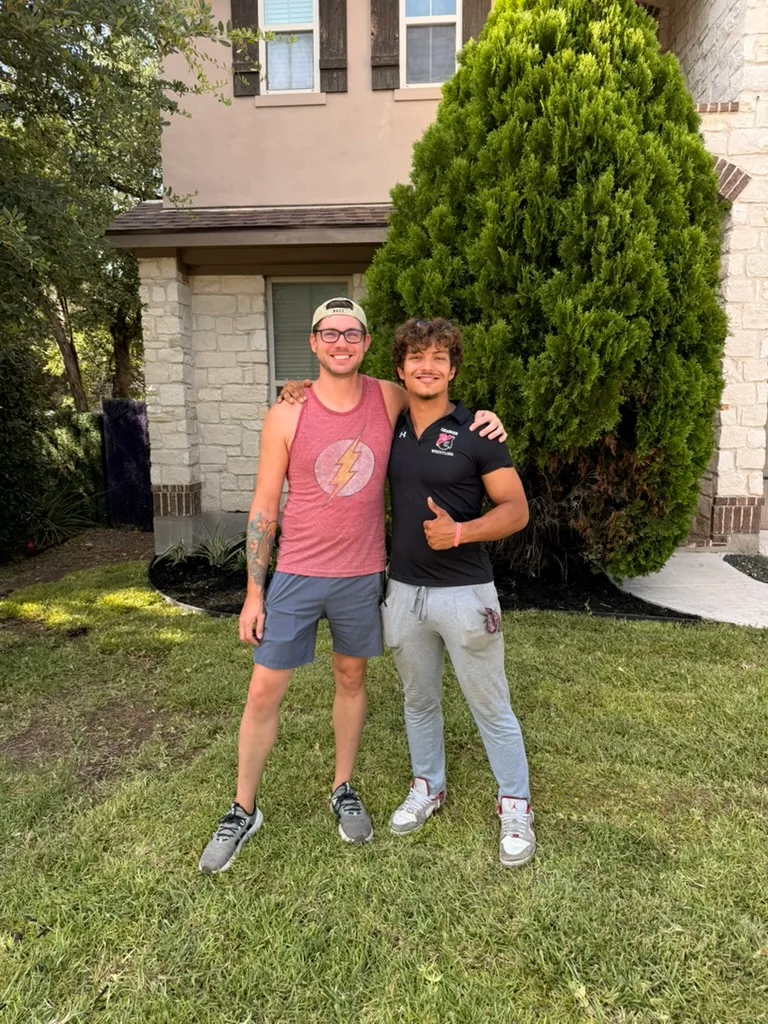 A satisfied Canopy Land Solutions homeowner with a crew member in front of their freshly landscaped San Antonio home